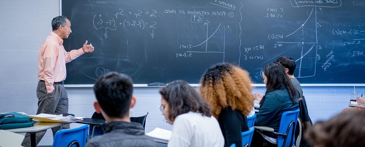 Professor of Economics Linus Yamane writing on the blackboard in a class.
